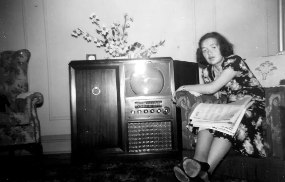Femeie într-un fotoliu lângă un televizor cu radio, fotografie din 1954